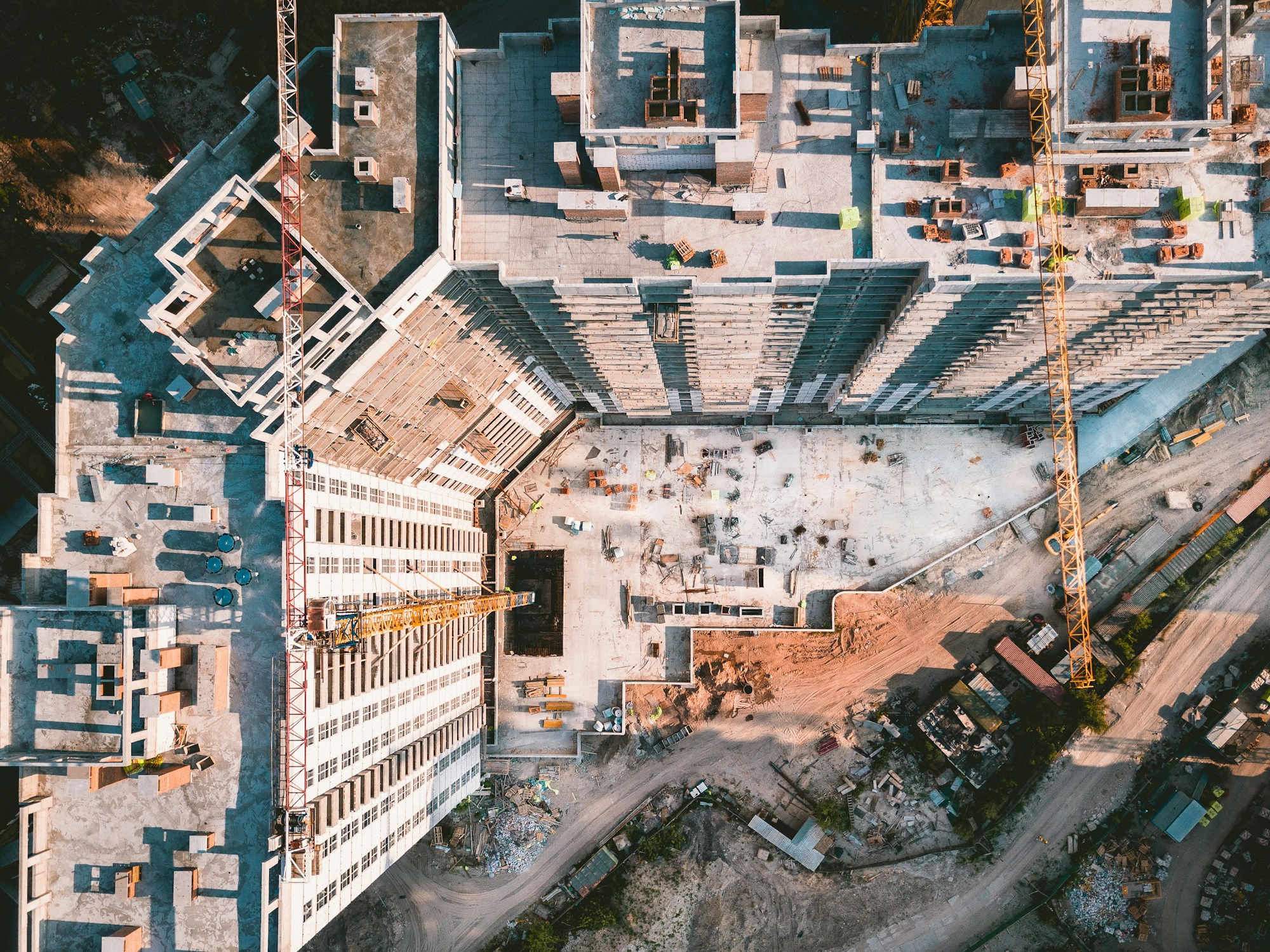 Aerial perspective of an active construction site with concrete floors and cranes